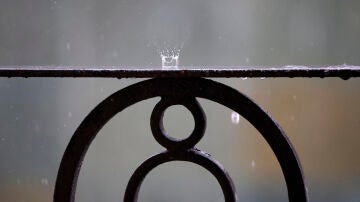 Detalle de la lluvia cayendo sobre la barandilla de un balcón.