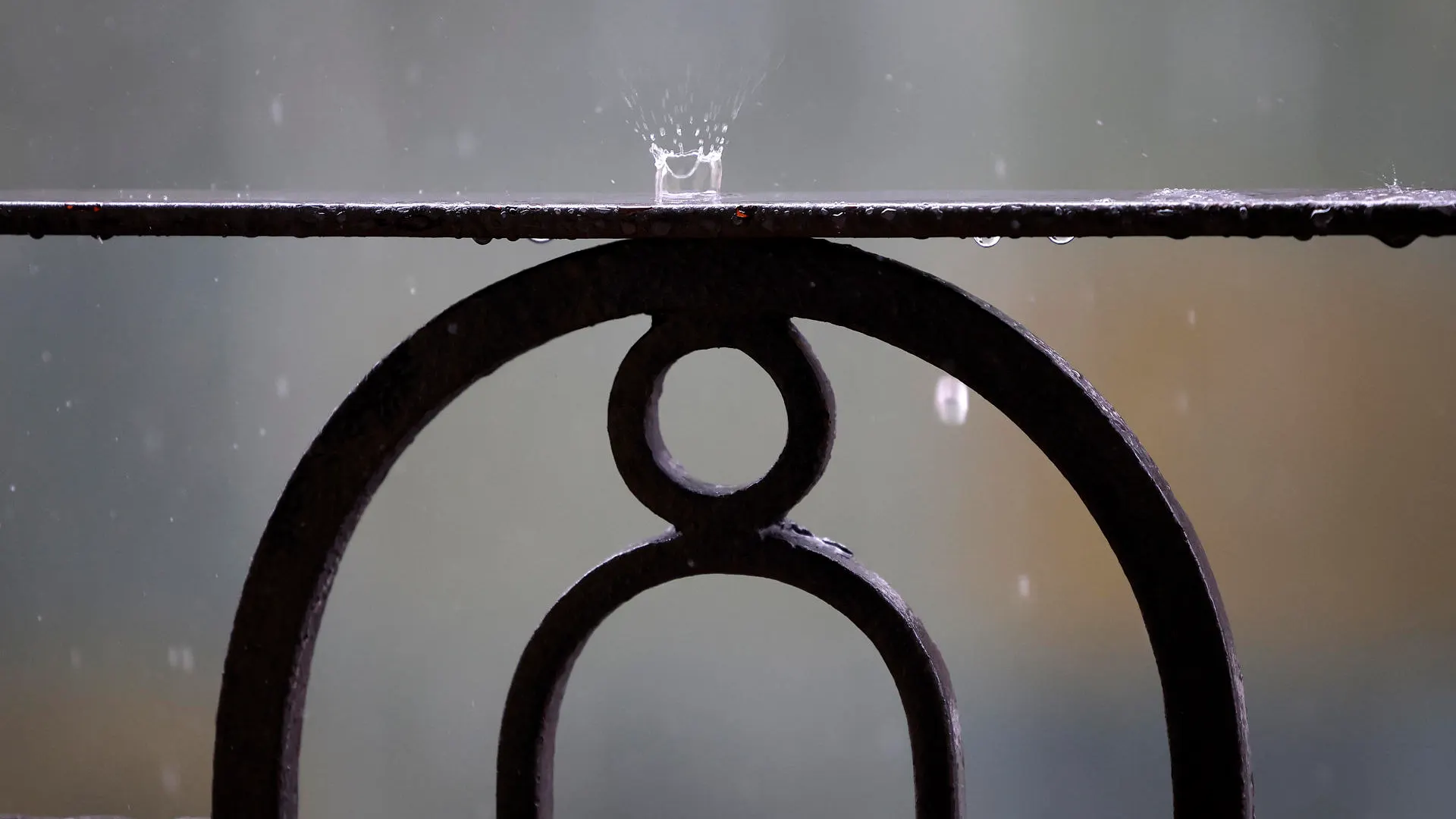 Detalle de la lluvia cayendo sobre la barandilla de un balcón.