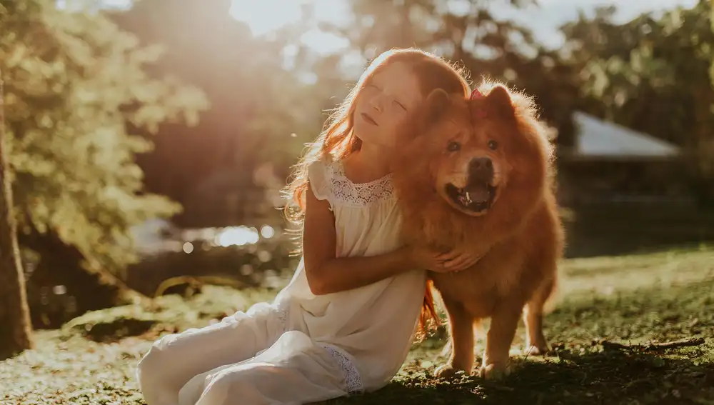 Una niña abraza a su perro.