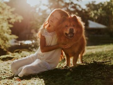 Una niña abraza a su perro.