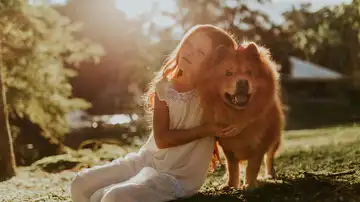 Una niña abraza a su perro. Una niña abraza a su perro.