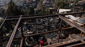 Personas retiran escombros de las viviendas destruidas por un incendio en Valparaíso (Chile)