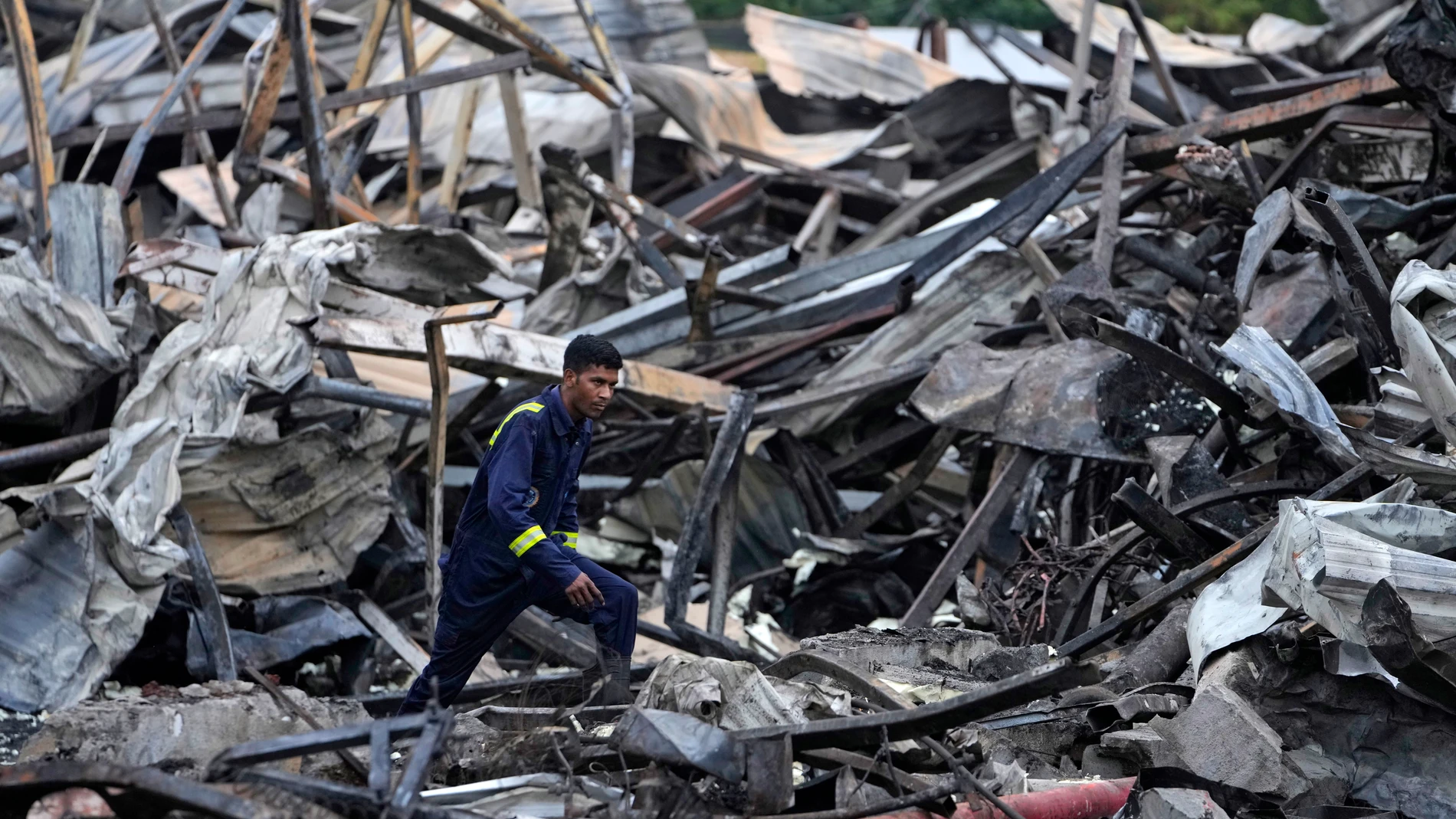 Un operario busca supervivientes entre los escombros del edificio incendiado en India
