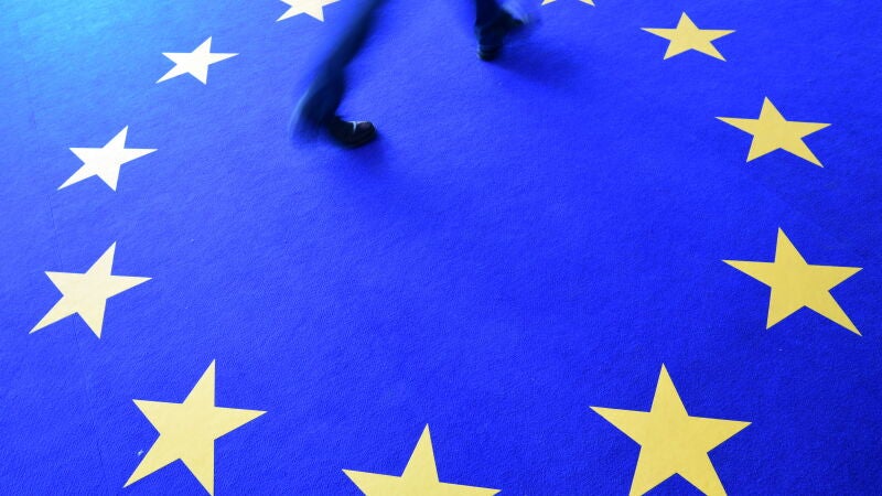 Un hombre camina sobre el logo de la Unión Europea