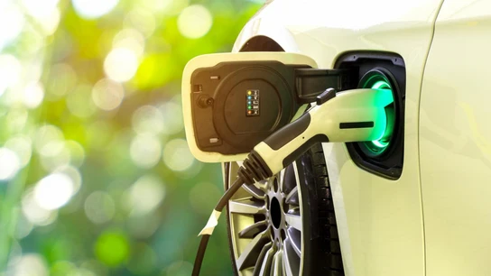 Los coches eléctricos se imponen al diésel y gasolina en materia de sostenibilidad. Un coche eléctrico en proceso de carga con fondo de naturaleza.