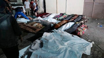 Los palestinos revisan los cuerpos de sus familiares asesinados por Israel en la escuela de la UNRWA en Gaza