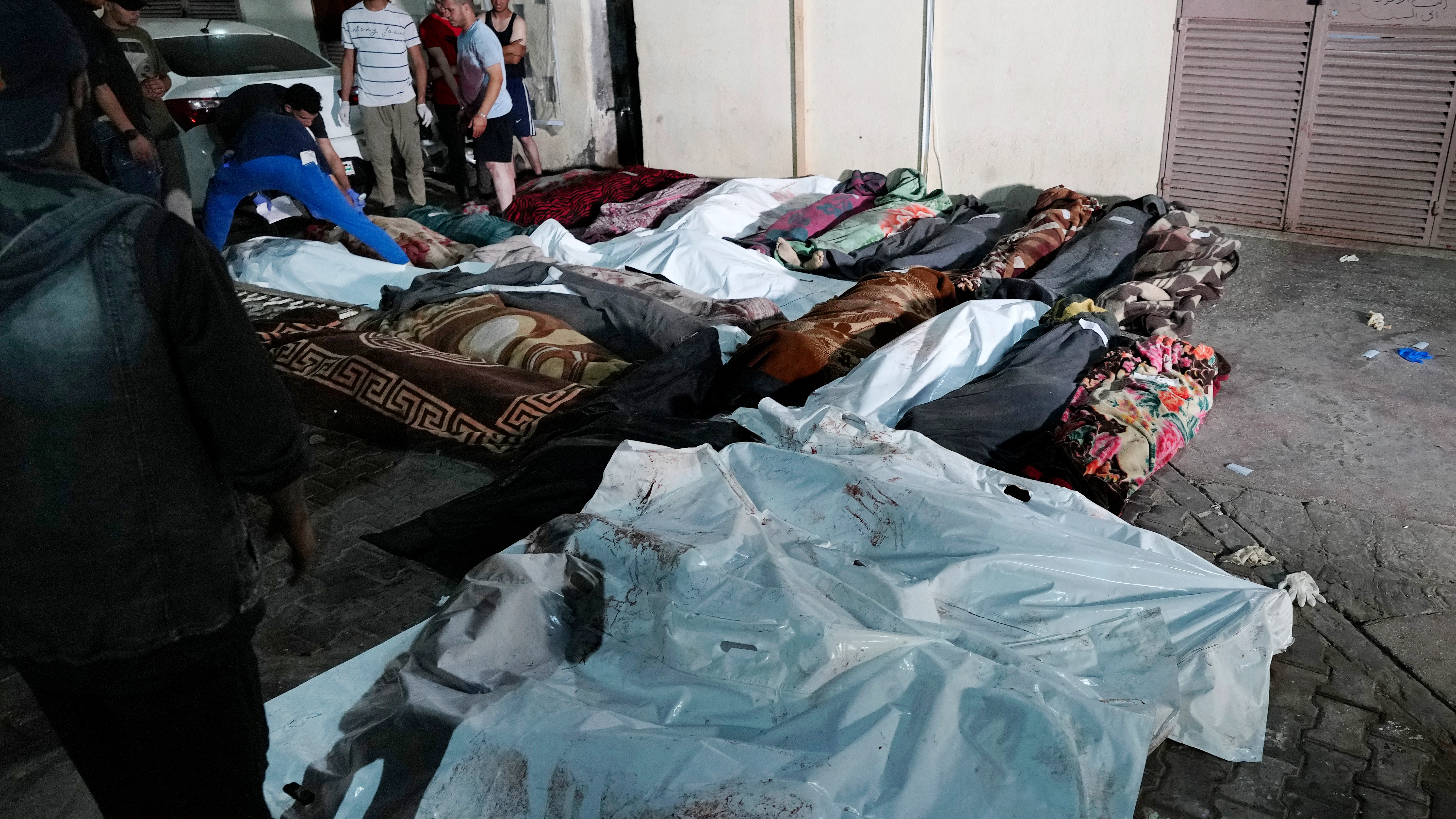 Los palestinos revisan los cuerpos de sus familiares asesinados por Israel en la escuela de la UNRWA en Gaza