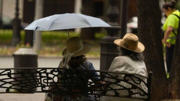 Dos personas con un paraguas en un banco