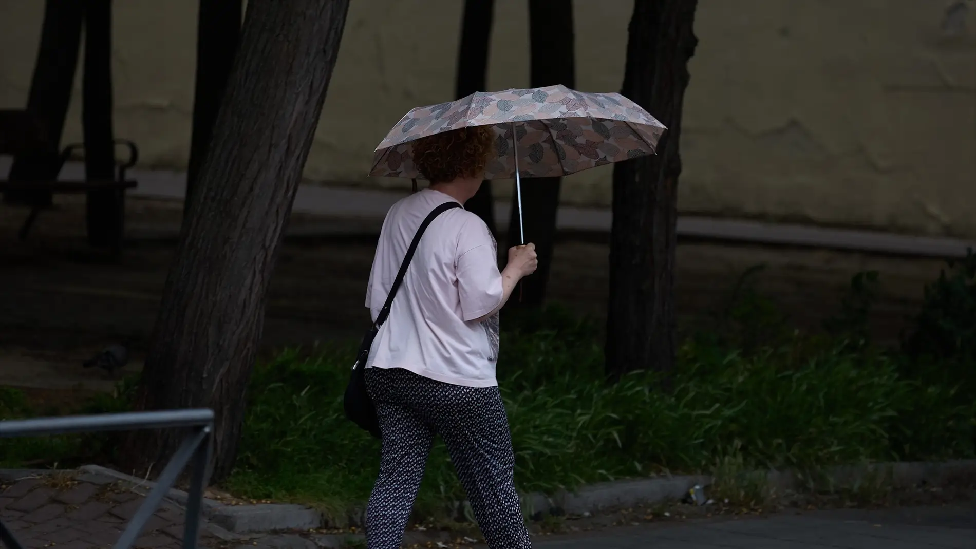 Una mujer utiliza un paraguas para protegerse de la lluvia Una mujer utiliza un paraguas para protegerse de la lluvia