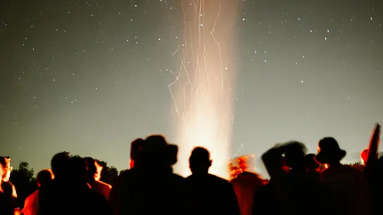 Varias personas en torno a una hoguera bajo un cielo nocturno estrellado Varias personas en torno a una hoguera bajo un cielo nocturno estrellado