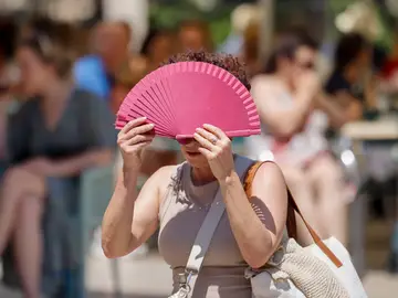 Una mujer se protege con un abanico del sol y del calor