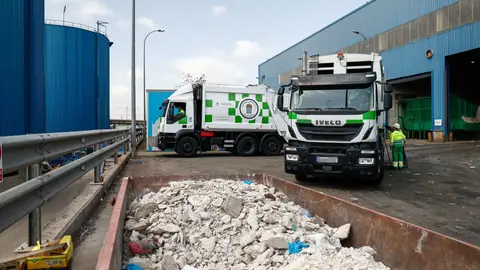 Un contenedor con escombros juntoa dos camiones de basura del Ayuntamiento de Madrid, a las puertas del Parque Tecnológico de Valdemingómez