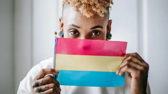 Una mujer con una bandera pansexual  Una mujer con una bandera pansexual