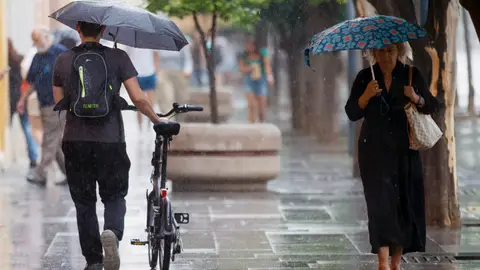 Varias personas se protegen con paraguas de la lluvia en el centro de Sevilla