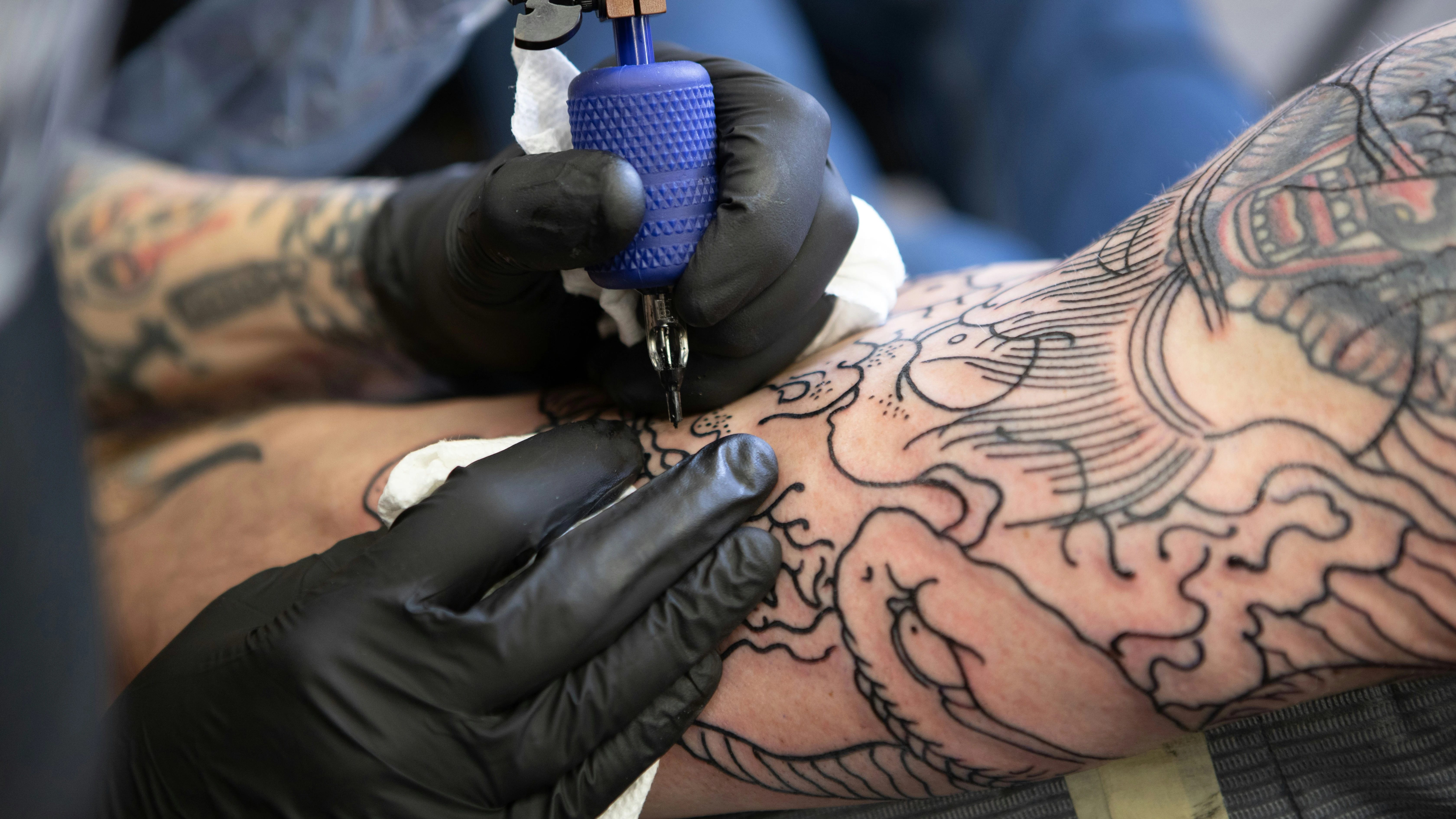 Un tatuador realiza un tatuaje con tinta negra en un brazo.