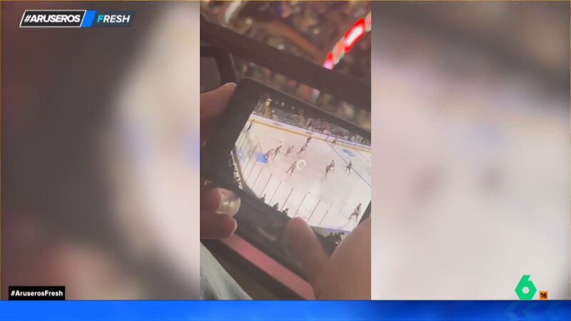 Un joven paga una entrada para ver un partido de hockey y decide ver otro partido en el móvil desde la grada