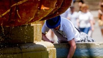 Un turista se refresca en una fuente en Sevilla.