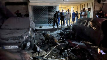 Varias personas inspeccionan coches dañados en los suburbios del sur de Beirut, Líbano, tras el ataque aéreo israelí. 