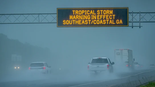 Los vehículos pasan bajo una señal de advertencia de tormenta tropical vigente debido a la tormenta tropical Debby en Waverly, Georgia Los vehículos pasan bajo una señal de advertencia de tormenta tropical vigente debido a la tormenta tropical Debby en Waverly, Georgia