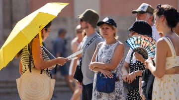 Un grupo de personas se protege del calor con parasol, abanico y gorras en la ciudad de València.