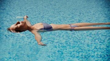 Una mujer, se relaja flotando en una piscina.