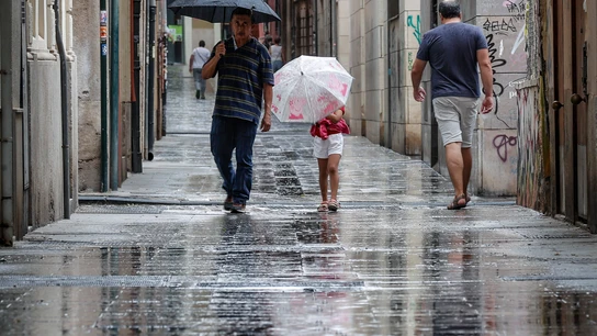 Varias personas caminan bajo la lluvia por una calle del centro de Valencia Varias personas caminan bajo la lluvia por una calle del centro de Valencia