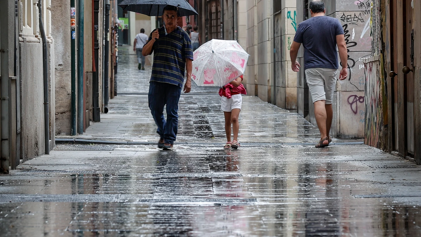 Varias personas caminan bajo la lluvia por una calle del centro de Valencia Varias personas caminan bajo la lluvia por una calle del centro de Valencia