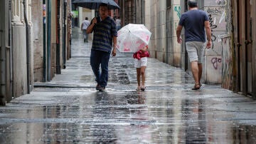 Varias personas caminan bajo la lluvia por una calle del centro de Valencia