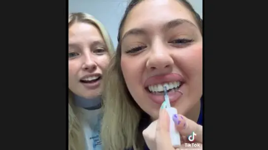 Dos chicas pintándose los dientes con esmalte de uñas Dos chicas pintándose los dientes con esmalte de uñas