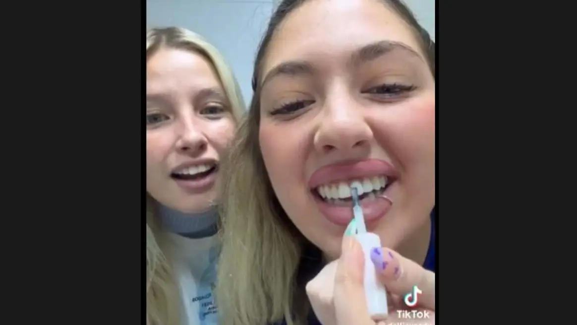 Dos chicas pintándose los dientes con esmalte de uñas