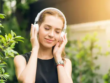 Una mujer escucha música a través de los auriculares Una mujer escucha música a través de los auriculares