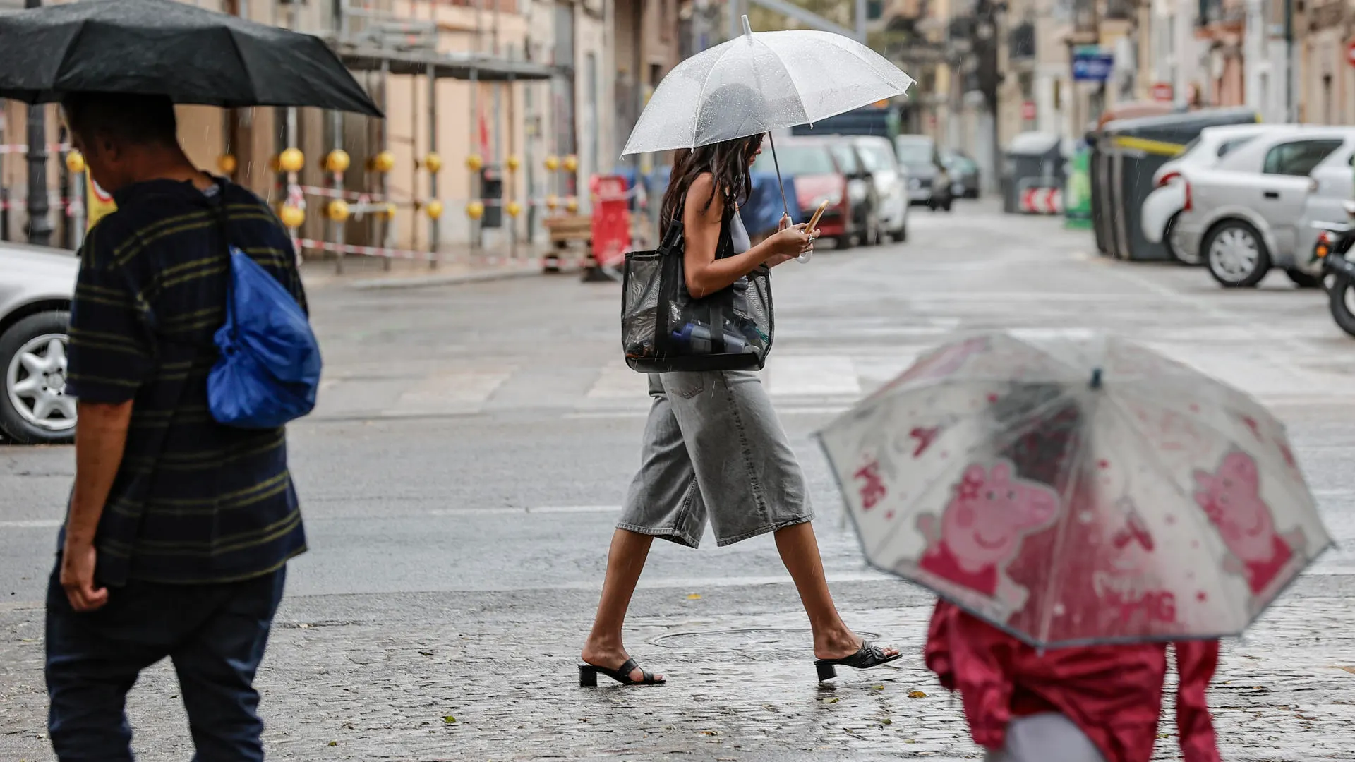 Varias personas caminan bajo la lluvia.