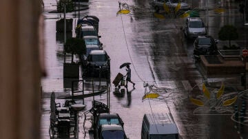 Un hombre cruza una calle en del centro de Elche mientras cae un fuerte aguacero este jueves.