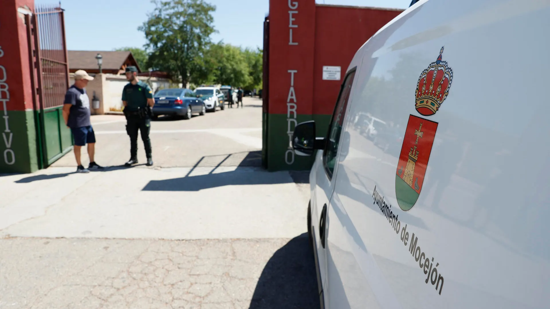 Un agente de la Guardia Civil habla con un vecino en la entrada al campo de fútbol de Mocejón (Toledo) donde un niño de 11 años fue asesinado el domingo.