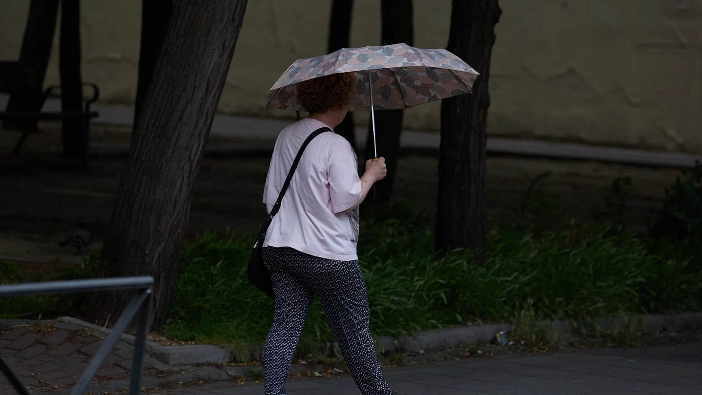 Una mujer se protege de la lluvia con un paraguas. Una mujer se protege de la lluvia con un paraguas.
