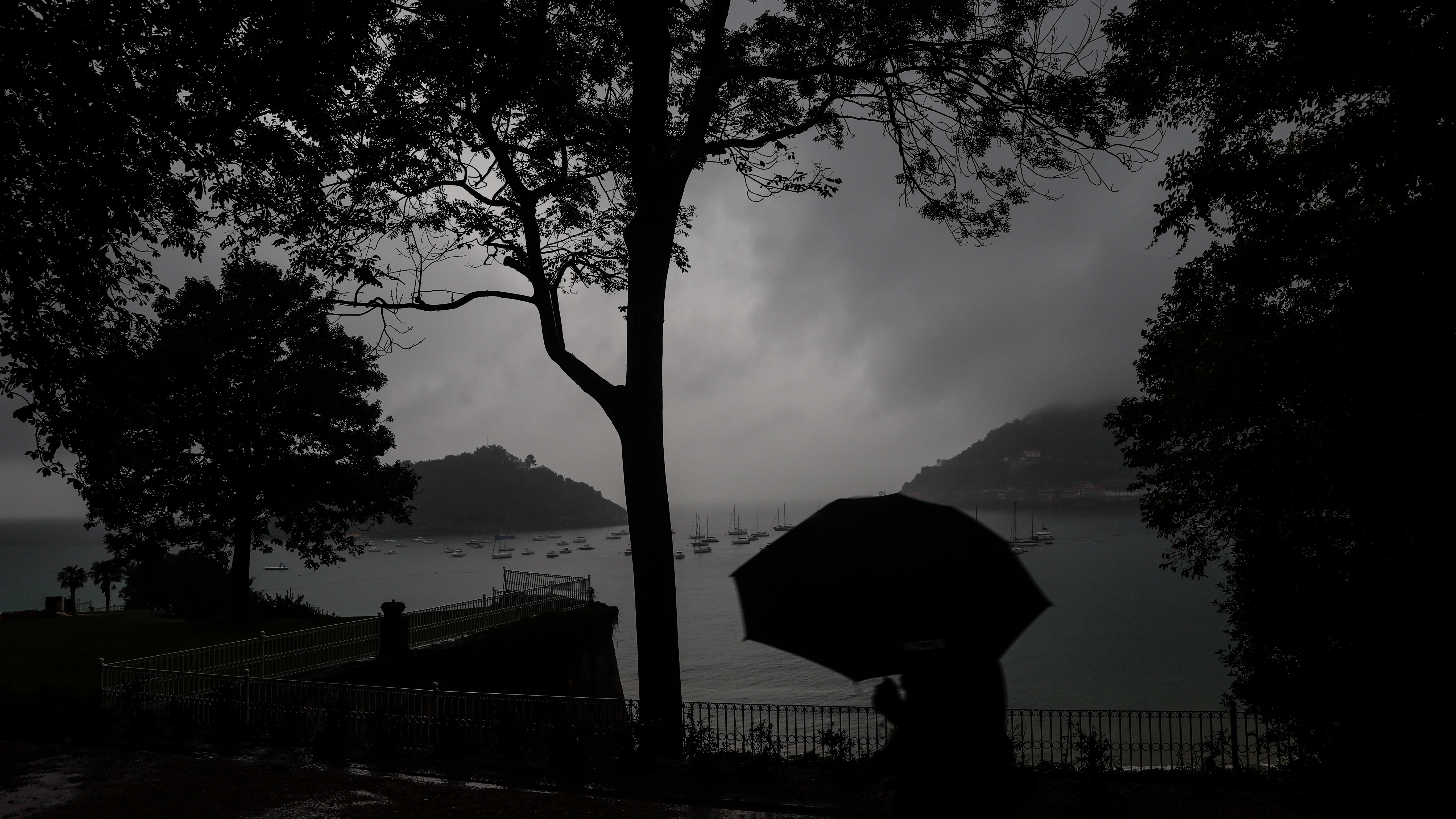Un hombre se protege con el paraguas de una fuerte tormenta en el paseo de la Concha de San Sebastián. E