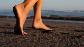 Una persona andando descalza por la playa. 