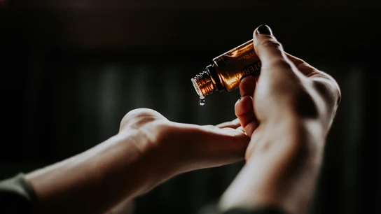 Una persona vierte unas gotas de aceite esencial en su mano. Una persona vierte unas gotas de aceite esencial en su mano.