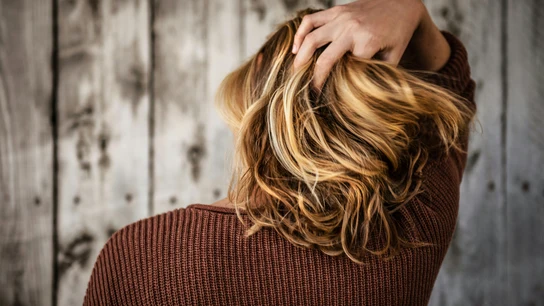 Imagen de una mujer de espaldas, tocando su melena. Imagen de una mujer de espaldas, tocando su melena.