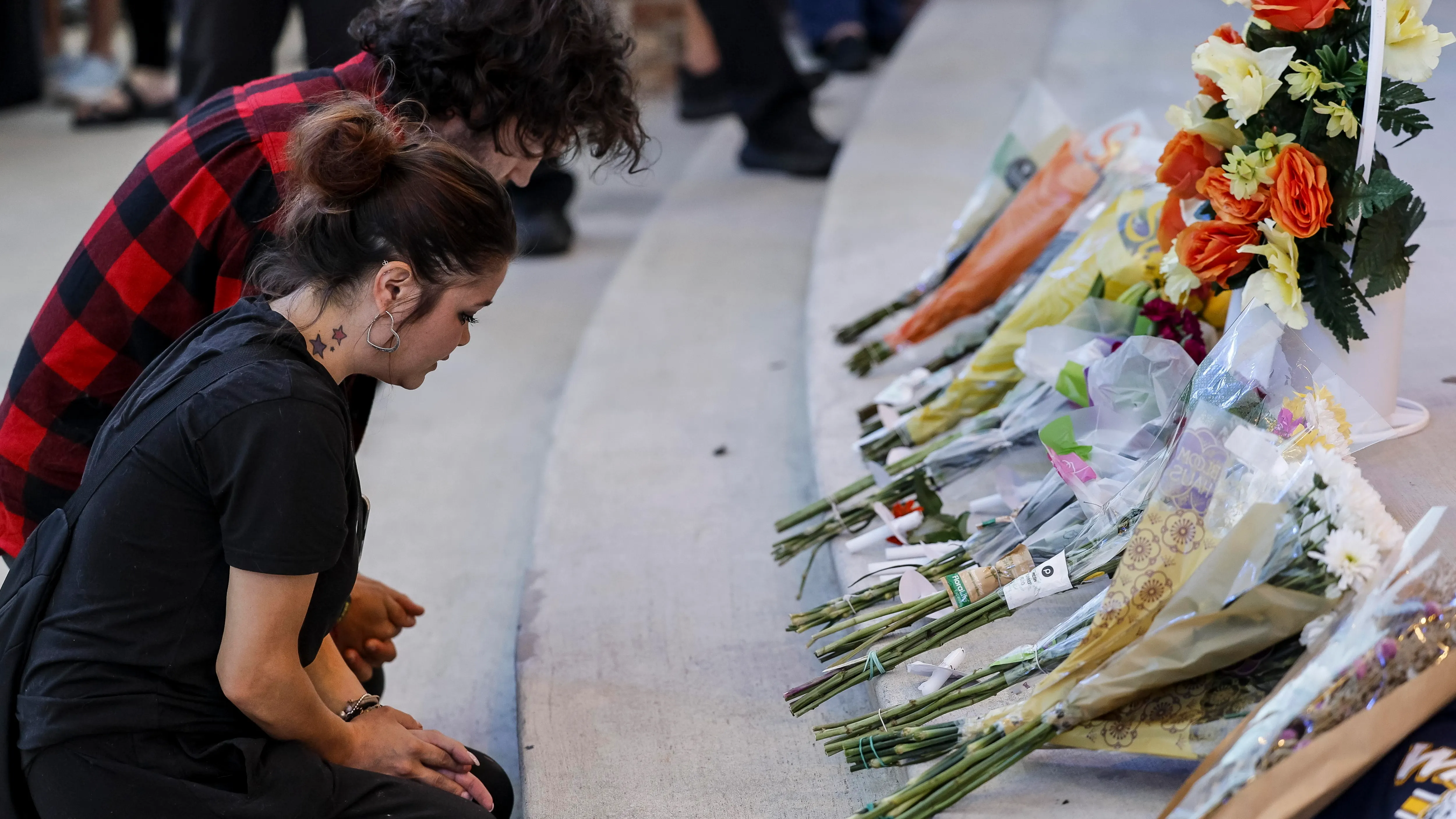 Varias personas se reúnen frente a un monumento conmemorativo por las víctimas de un tiroteo escolar en Georgia