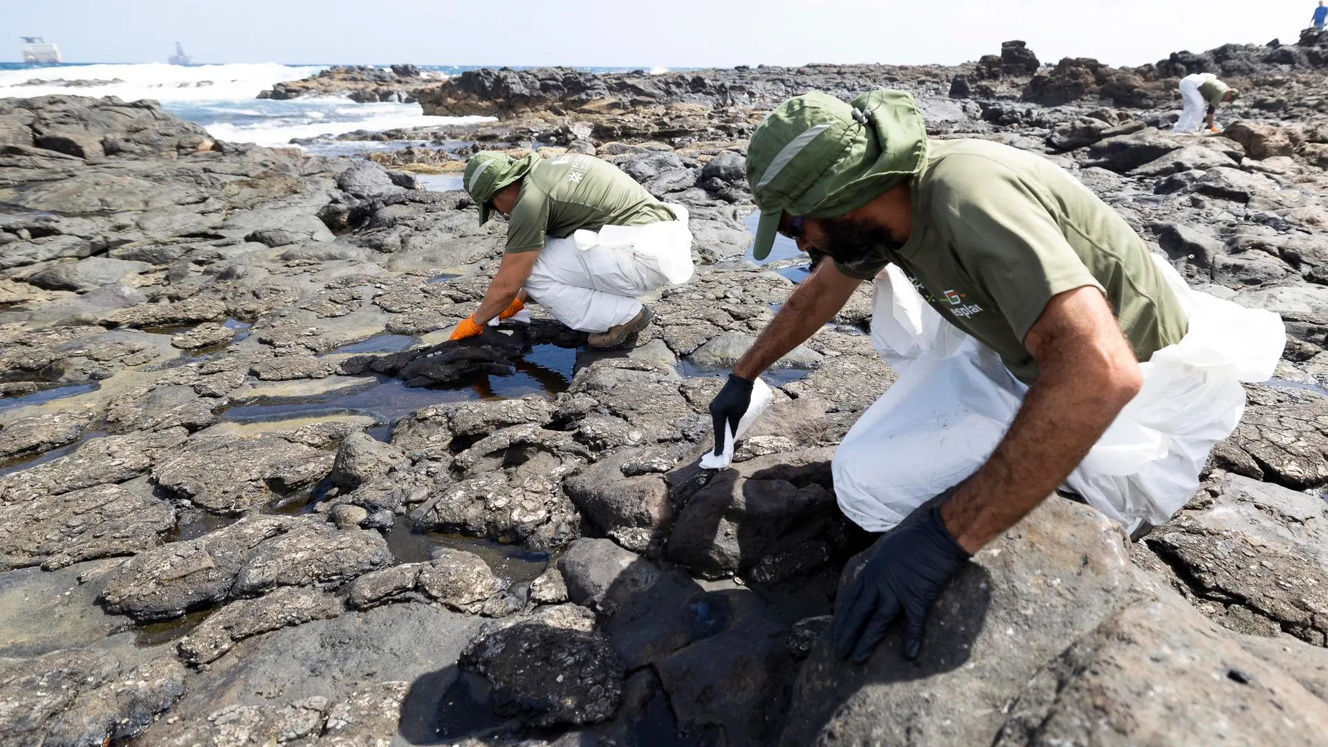 Efectivos de los equipos de limpieza retiran restos del vertido de fuel en una playa de Telde