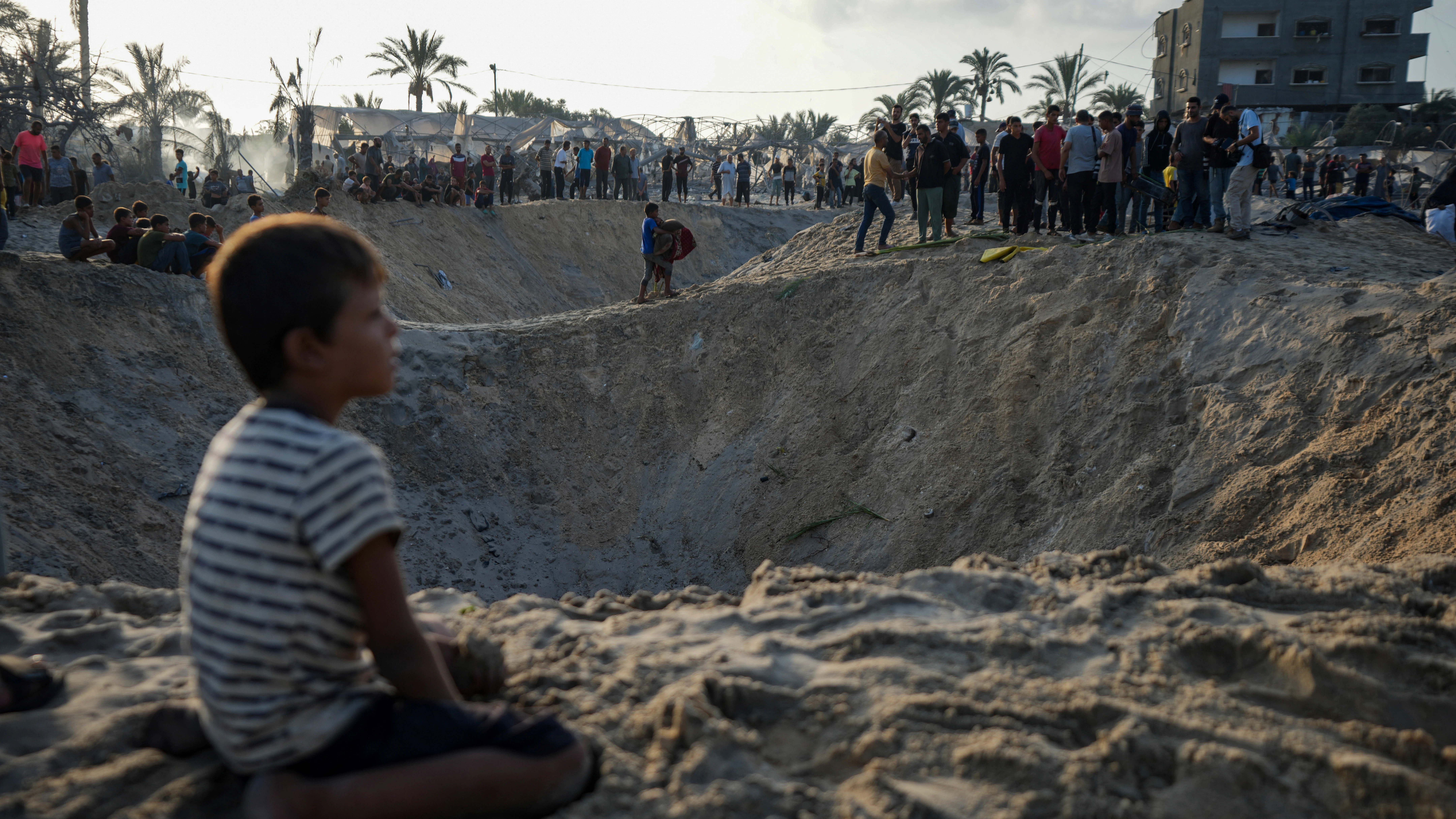 Palestinos observan la destrucción después de un ataque aéreo israelí contra un campo de refugiados lleno de palestinos desplazados por la guerra en Muwasi. 