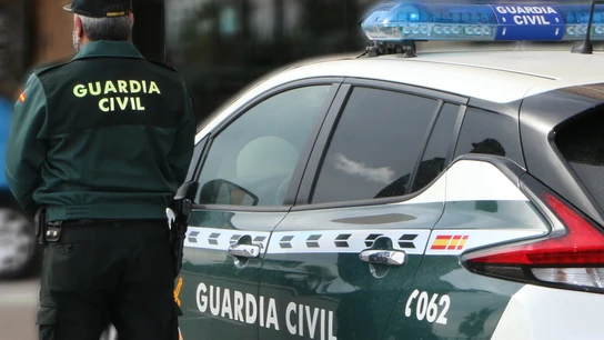 Un agente de la Guardia Civil, de espaldas, de pie junto a un vehículo oficial. Un agente de la Guardia Civil, de espaldas, de pie junto a un vehículo oficial.