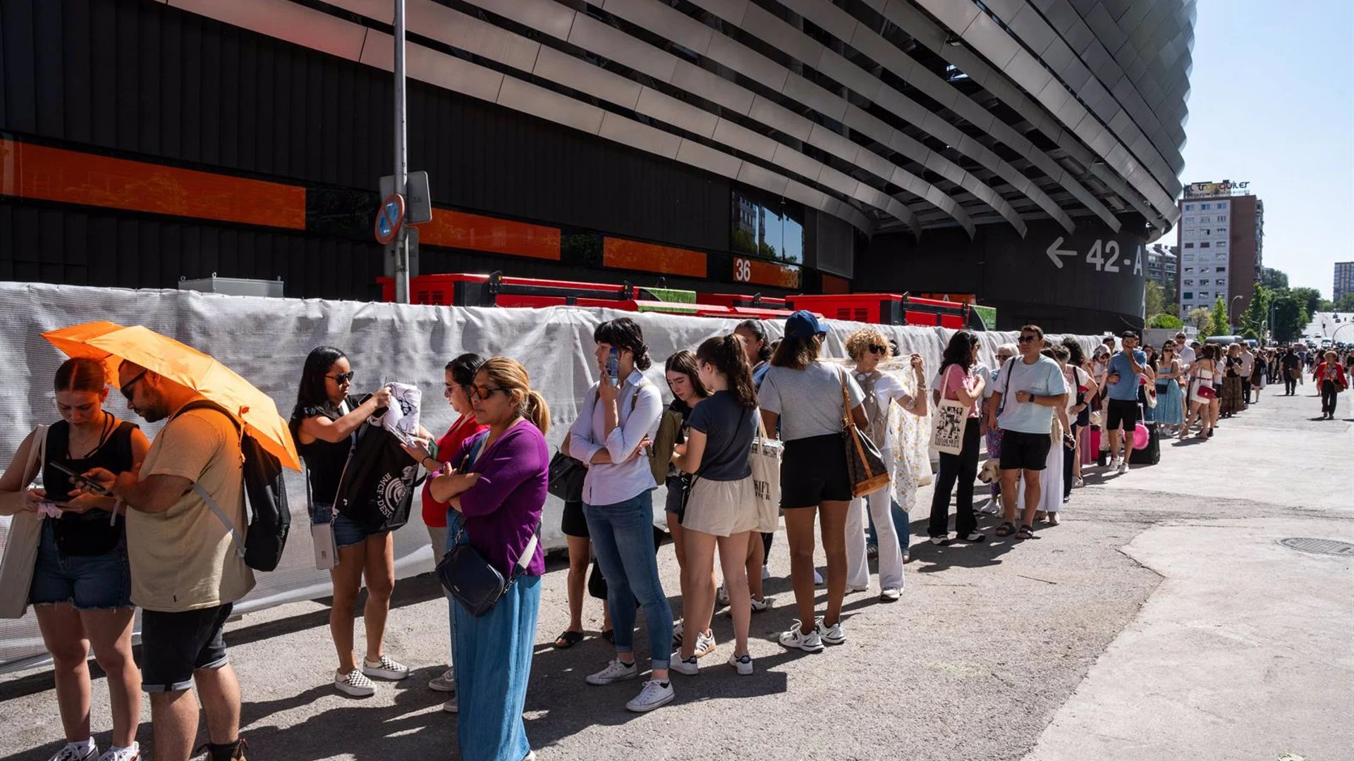 Varias personas esperan en fila a las afueras del estadio Santiago Bernabé de Madrid.