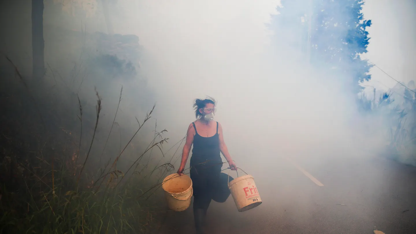 Una mujer carga cubos mientras los vecinos luchan contra el incendio en Sever do Vouga (Aveiro), este martes. Una mujer carga cubos mientras los vecinos luchan contra el incendio en Sever do Vouga (Aveiro), este martes.