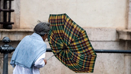 Un hombre intenta protegerse de la lluvia con un paraguas Un hombre intenta protegerse de la lluvia con un paraguas