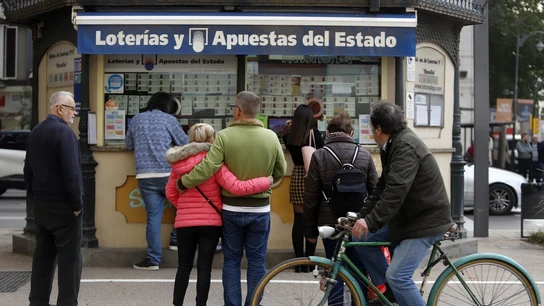 Una pareja le da un sobre con 4.100 euros a una persona sin hogar que dormía en una administración de Lotería Gente esperando para comprar lotería a las puertas de una administración