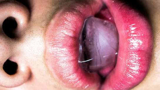 Primer plano de unos labios sosteniendo un cubito de hielo. Primer plano de unos labios sosteniendo un cubito de hielo.