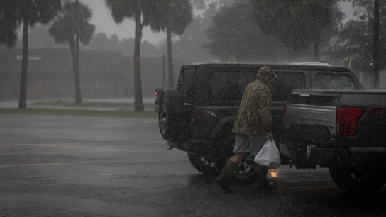 Un hombre camina bajo la lluvia ante la inminente llegada del huracán Helene. Un hombre camina bajo la lluvia ante la inminente llegada del huracán Helene.