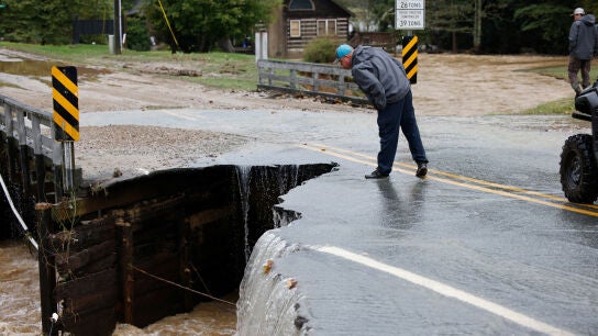 Un transeúnte inspecciona la parte derrumbada de un puente después de que las aguas de la inundación lo destruyeran durante la tormenta tropical Helene 